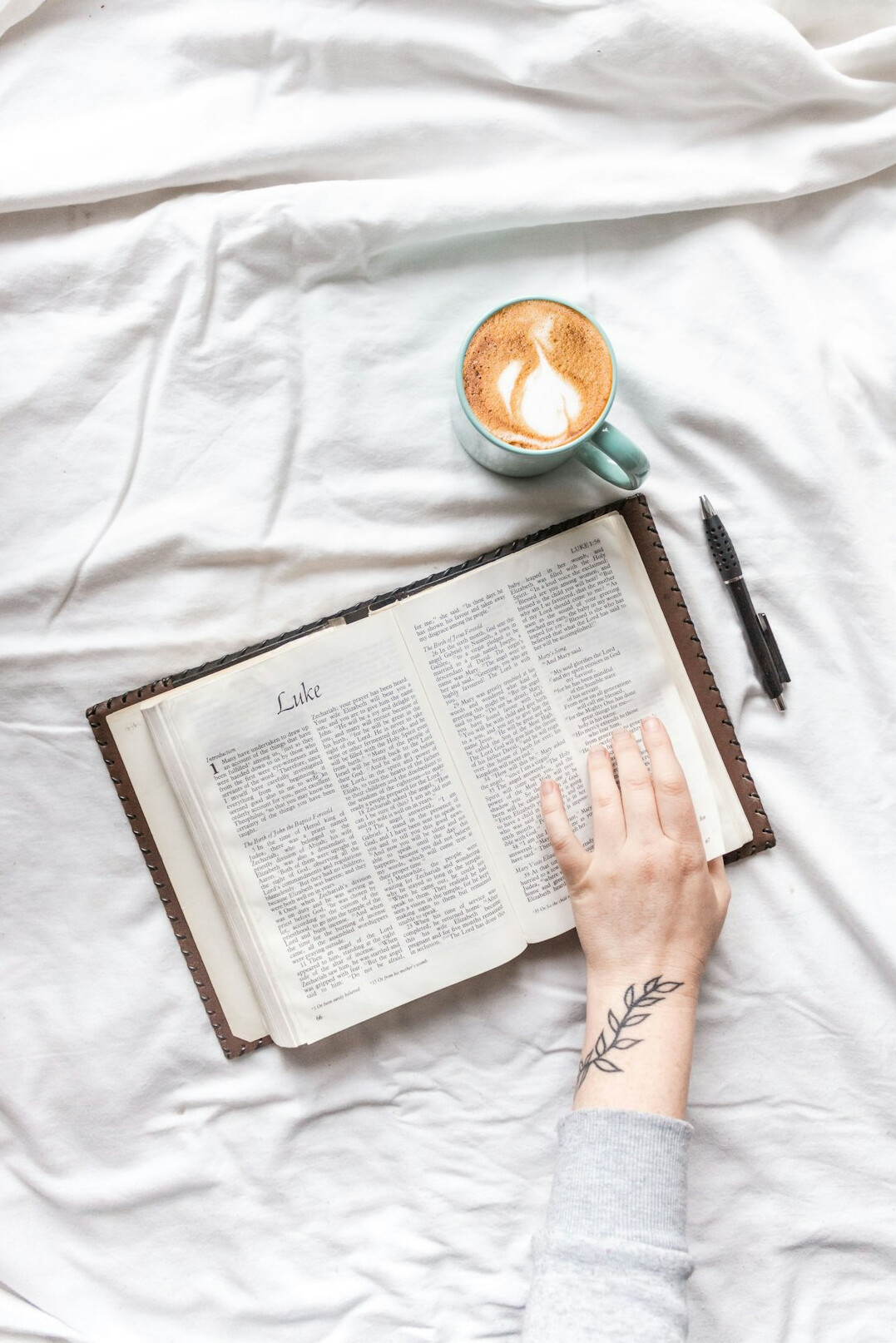 Hands writing in a journal beside a cup of coffee